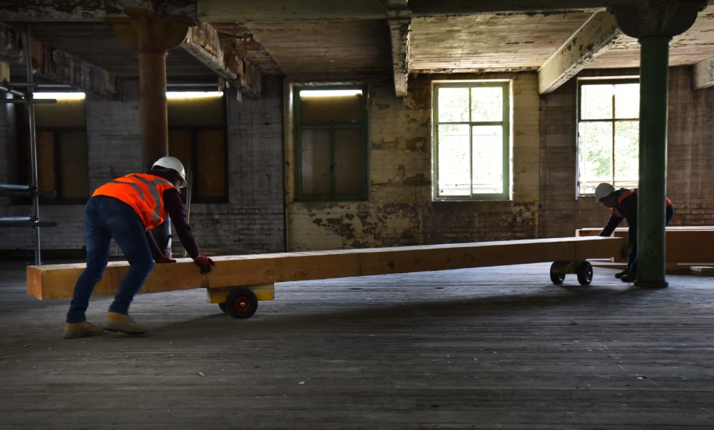 The Priestley Construction team transporting a wooden beam during the refurbishment of Conditioning House, Bradford